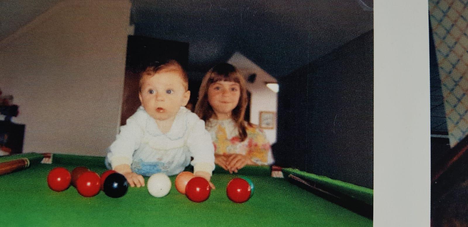 Jack as a baby at a pool table, surrounded by billiard balls, with another child beside him.