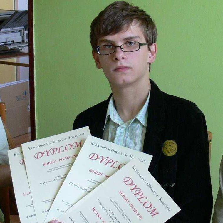 Rob at school, wearing glasses and holding a collection of physics certificates.